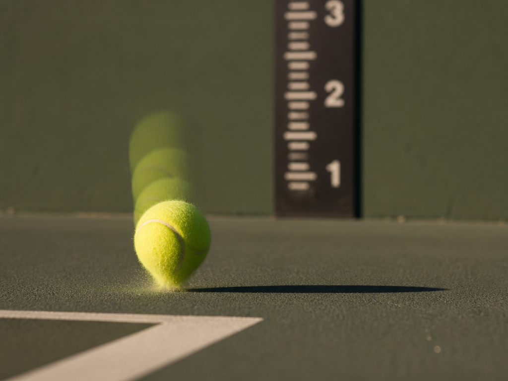 A high-speed photographic study of a single tennis ball mid-bounce, frozen in sharp detail…
