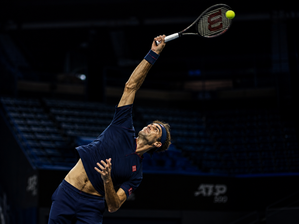 A dramatic low-angle action photograph of a tall male professional tennis player at the…