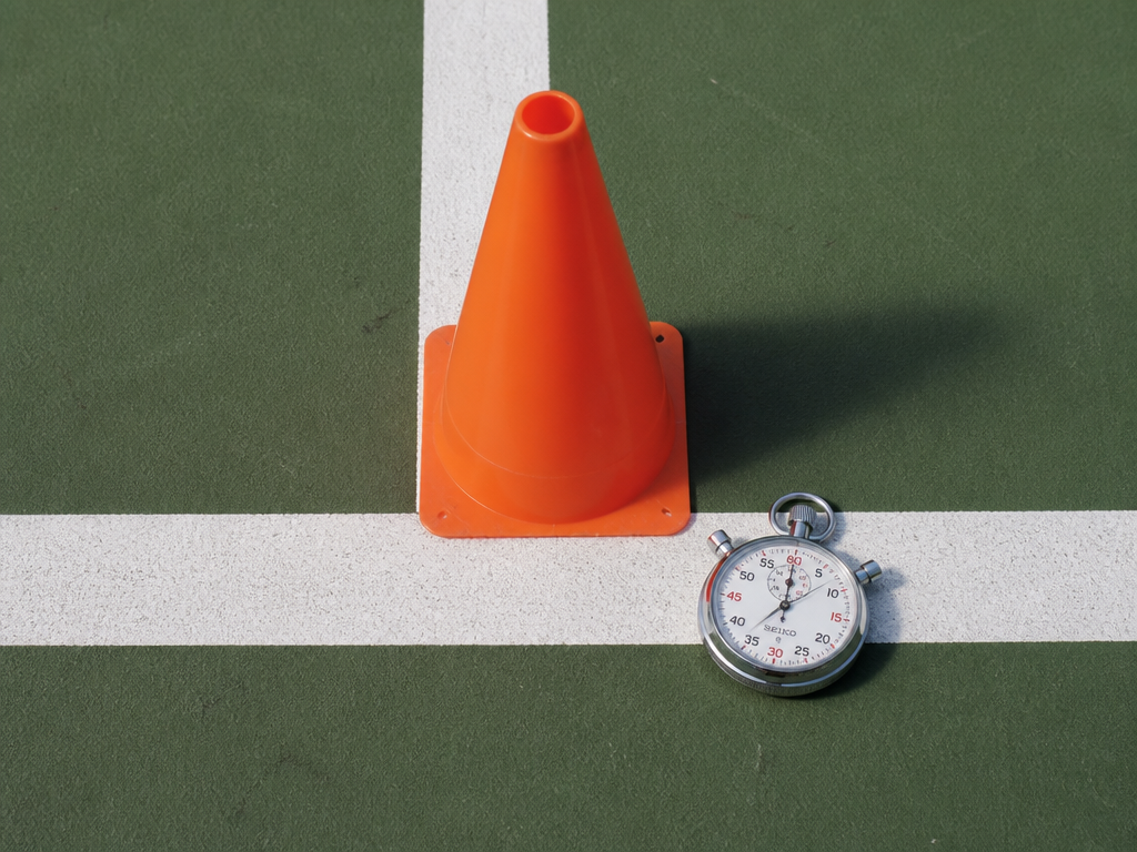 Close-up overhead detail of a single orange cone resting precisely on the white painted…