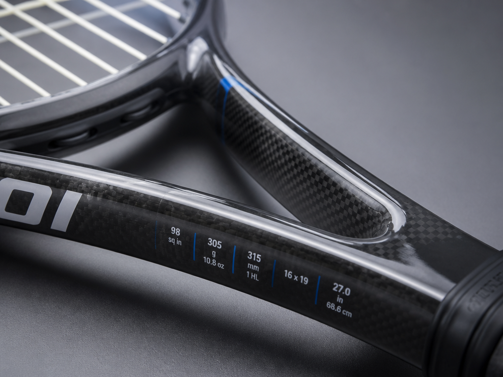 Extreme close-up macro photograph of a modern tennis racquet's throat and beam resting on…