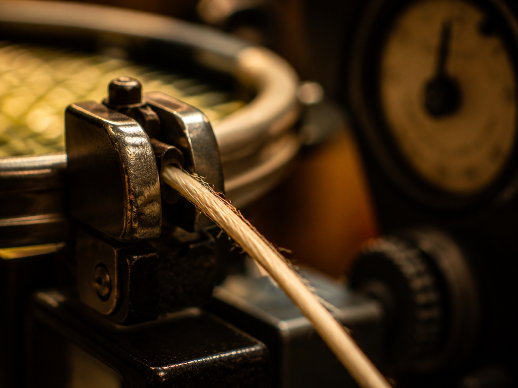 Extreme close-up macro photograph of a tennis racquet stringing machine in a dim pro…
