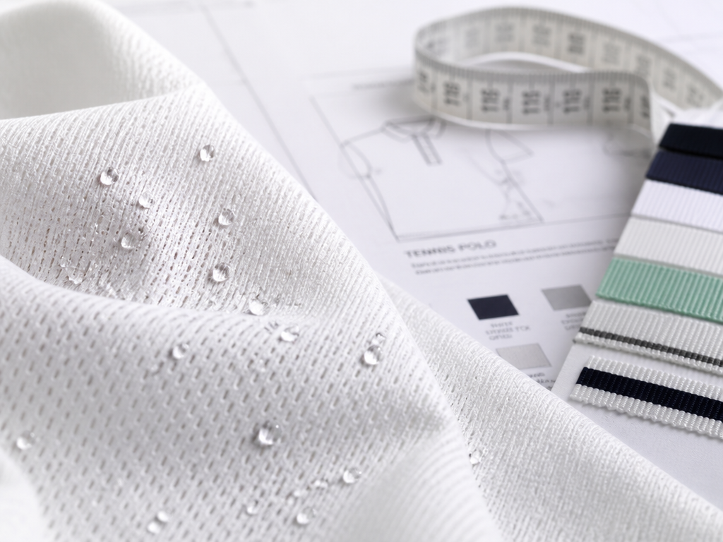 Macro still-life photograph of white polyester tennis fabric draped over a design studio table…