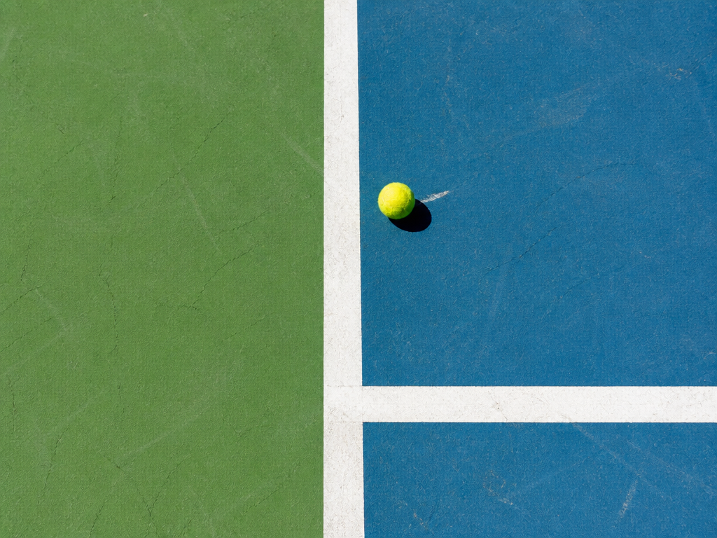 A tight overhead detail shot of an empty tennis court's service box and sideline…