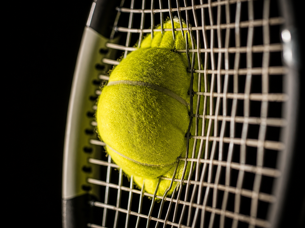 Extreme macro photograph of a tennis ball at the instant of impact against a…